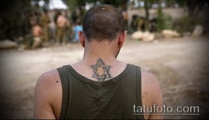 Фото тату: Звезда Давида на шее мужчины в военной форме. Татуировка выполнена в черном цвете, с тонкими линиями и небольшими тенями.