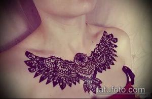 Фото татуировки мехенди сова на груди. Черный узор совы с детализированными крыльями и геометрическими элементами.