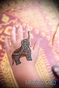 Фото тату слона на ладони в стиле мехенди. Детализированный рисунок с использованием темных оттенков и сложных узоров.