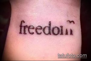 Фото тату простой надписи 'freedom' на запястье, выполненной черными чернилами. Минималистичный дизайн и четкий шрифт.