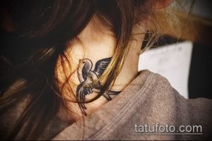 Фото тату ласточки на шее. Черно-серая татуировка с детально проработанными крыльями и изящным силуэтом птицы. Идеальный эскиз тату для девушек.