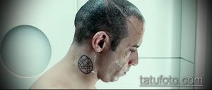 Фото тату оккультного символа на затылке. Чёрный рисунок татуировки, выполненный в минималистичном стиле, с геометрическими формами.