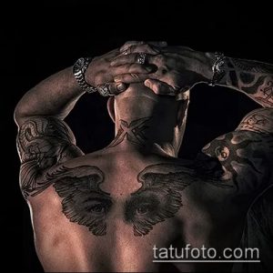 Фото тату крыльев ангела на спине мужчины. Детализированный рисунок с изображением глаз в крыльях, выполненный в черных тонах.