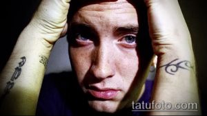Фотография Эминема с татуировками на запястьях. Видны небольшие черные рисунки, возможно, символы или надписи.
