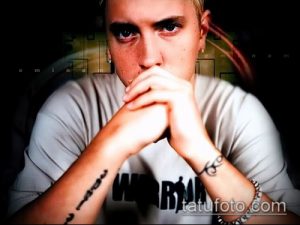Фотография Эминема с задумчивым взглядом и татуировками на руках, используемая как эскиз для татуировки.