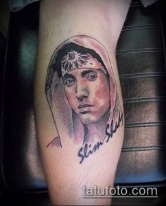Фото тату с изображением Эминема в молодости, с подписью 'Slim Shady', выполненное в реалистичном стиле на предплечье.