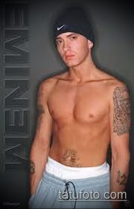 Фото татуировки на плече и руке с изображением портрета и надписи 'EMINEM'. Черно-серые тона, детализированный рисунок.