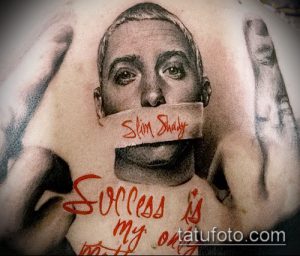 Фото татуировки с реалистичным портретом Эминема на груди. Надпись 'Slim Shady' на лице и фраза 'Success is my only option' под портретом.