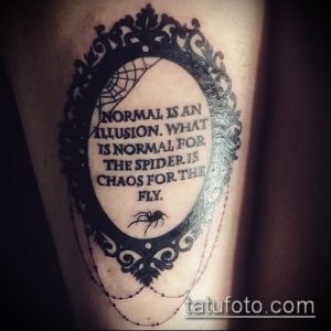 Фото татуировки на руке с изображением цитаты "Normal is an illusion. What is normal for the spider is chaos for the fly.", заключенной в старинную рамку с пауком.