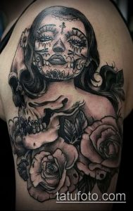 Фото тату: красочная татуировка в стиле сахарной черепушки (Santa Muerte) с розами на плече, выполненная в реалистичной технике.