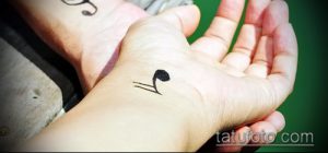 Фото тату: маленькая черная нота на ладони руки. Минималистичный рисунок татуировки для меломанов.