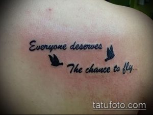 Фото небольшой татуировки на плече с надписью 'Everyone deserves to fly' и изображением двух летящих птиц. Черный цвет, минималистичный стиль.