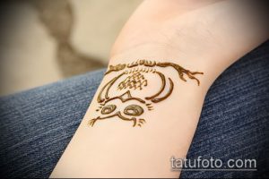 Фото временной татуировки совы на запястье. Рисунок выполнен в коричневых тонах, с мультяшным стилем и выразительными глазами.