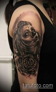Черно-серая татуировка на плече с изображением сахарной черепушки (Calavera) и розы.
