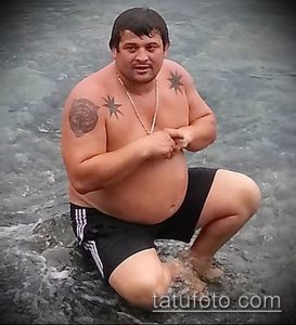 Фото тату головы медведя на плече мужчины. Рядом с медведем изображены звезды. Черно-белый рисунок татуировки.