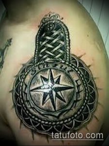 Фотография татуировки на плече, изображающей компас, окруженный сложными узорами и геометрическими фигурами. Черно-серый рисунок.