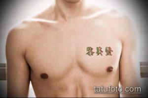 Фотография татуировки иероглифов на мужской груди. Тату выполнена в нескольких цветах, выглядит ярко и оригинально.