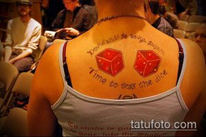 Фото тату на спине с изображением двух игральных кубиков и надписи 'Time to toss the dice'. Черно-белый рисунок.