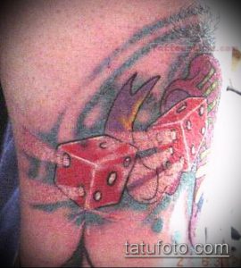 Фото яркой татуировки с красными игральными костями, сердцем и пламенем на руке.