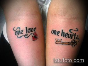 Фото тату на запястьях пары: надпись 'One Love' с красным сердцем и 'One Heart' с ключом. Нежные, минималистичные татуировки.