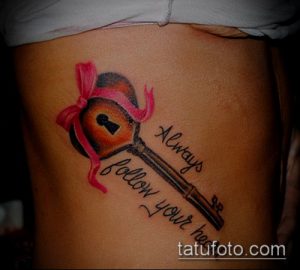 Фото тату на боку: стилизованный ключ с розовым бантом и надписью 'Always follow your heart'. Изящный дизайн.