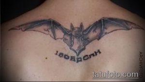 Фото тату летучей мыши на спине. Простой контурный рисунок, минималистичный стиль, надпись.