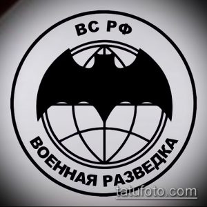 Фото тату с изображением эмблемы военной разведки: глобус с крыльями и надписью 'ВС РФ Военная Разведка'. Четкий, графичный рисунок.