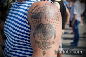 Фото тату на плече с изображением парашютиста и глобуса. Черно-белый рисунок татуировки с надписью на русском языке.