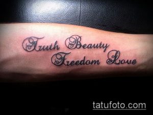 Фото тату на предплечье мужчины с надписью 'Truth Beauty Freedom Love'. Черно-белый рисунок татуировки выполнен каллиграфическим шрифтом.