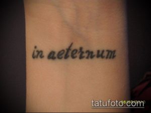 Фото тату: минималистичная татуировка с латинской фразой 'in aeternum' на запястье. Черные чернила, простой шрифт. Изящный и лаконичный рисунок.