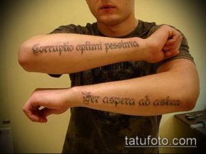 Фото тату: две латинские фразы 'Corruptio optimi pessima' и 'Per aspera ad astra' на предплечьях мужчины, выполненные черными чернилами в каллиграфическом стиле.
