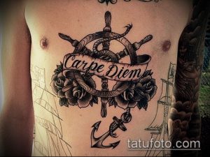 Фото тату с морской тематикой: штурвал, розы, якорь и надпись 'Carpe Diem'. Черно-белая татуировка, детальная проработка.