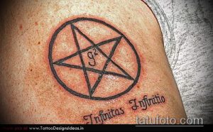 Фото тату на плече: пентаграмма в круге с надписью 'Infinitas Infinitio'. Черно-белый рисунок татуировки.