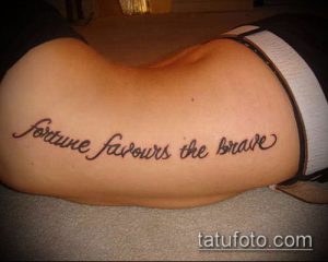 Фото тату на пояснице: надпись 'fortune favours the brave' красивым шрифтом. Черно-белый рисунок татуировки.
