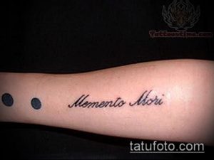 Фото тату надписи 'Memento Mori' на руке. Черный цвет, каллиграфический шрифт, минималистичный стиль. Идеи для тату надписей.