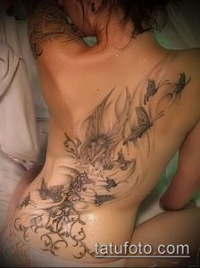 Фото тату: татуировка на боку и спине девушки, птицы, бабочки, цветы, детализированный рисунок татуировки.