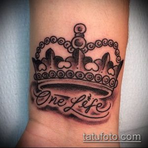 Фото тату короны с надписью 'One Life' на запястье. Черно-серый рисунок татуировки, выполненный в реалистичном стиле.