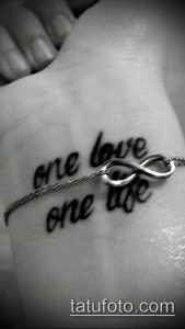 Фото тату на запястье с надписями 'one love' и 'one life', соединенных символом бесконечности. Нежная и романтичная татуировка.
