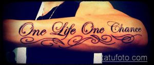 Фото тату на предплечье: черная надпись 'One Life One Chance' с декоративными завитками. Красивый рисунок татуировки для мужчин и женщин.