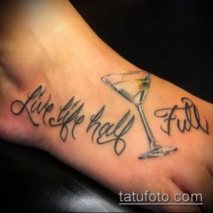 Фото тату надписи 'Live Life Half Full' с изображением бокала мартини на стопе. Цветная татуировка, выполненная в реалистичном стиле.