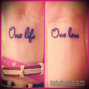 Фото тату надписи 'One Life' на внутренней стороне запястья, выполненной тонкими линиями черного цвета. Изящный шрифт и небольшие размеры.