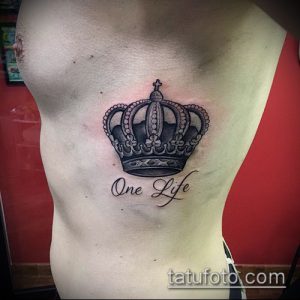Фото тату короны и надписи 'One Life' на боку. Черно-серая татуировка с детальной проработкой короны.
