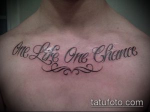 Фото тату надписи 'One Life One Chance' на груди. Черно-серая татуировка, выполненная каллиграфическим шрифтом с декоративными элементами.