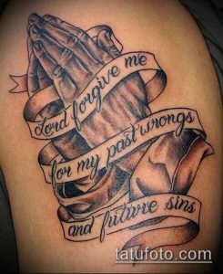 Фото тату на плече с изображением молящихся рук и надписи 'Lord forgive me for my past wrongs and future sins', выполненное в реалистичном стиле.