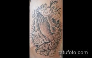 Фото тату на руке: молящиеся руки, окруженные розами и надписью 'Forever Lasts Our Love'. Черно-серый рисунок татуировки с романтическим подтекстом.