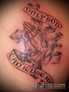 Фото тату на спине: молящиеся руки с четками и надписью 'Only God Can Judge Me'. Черно-белый рисунок татуировки в стиле реализм.