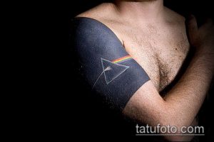 Фото тату на руке: минималистичное изображение призмы Pink Floyd с радугой, выполненное в черно-белых тонах.