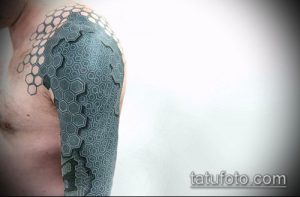 Фото тату: большая татуировка, покрывающая плечо и часть груди, выполнена в виде сложного геометрического узора из шестиугольников.