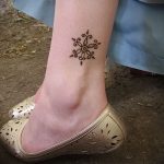 Фото тату мехенди на лодыжке, демонстрирующее простой, но элегантный узор в виде цветка. Идеально для тех, кто предпочитает минимализм и нежность.