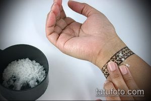Фотография руки, на которой наносится татуировка. Виден процесс подготовки кожи и нанесения рисунка.